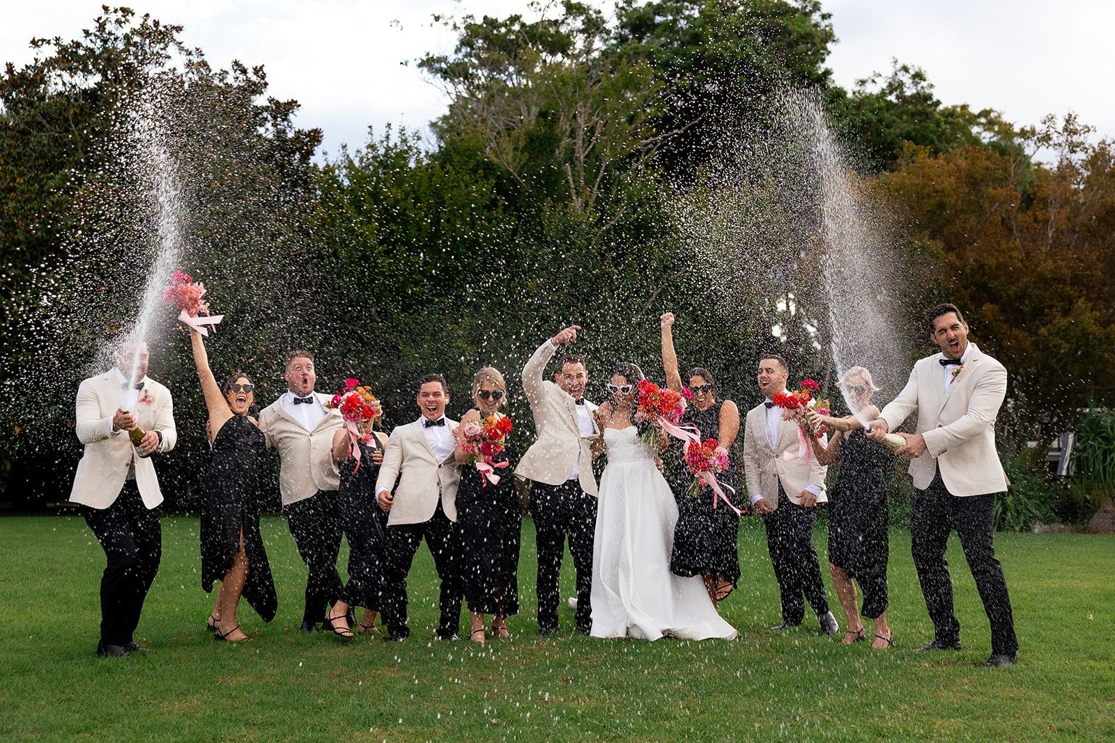 The bridal party spraying champagne on the lawn