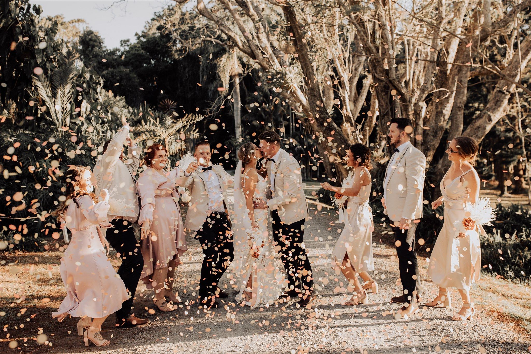 A bridal party throwing petals on the tree-lined driveway