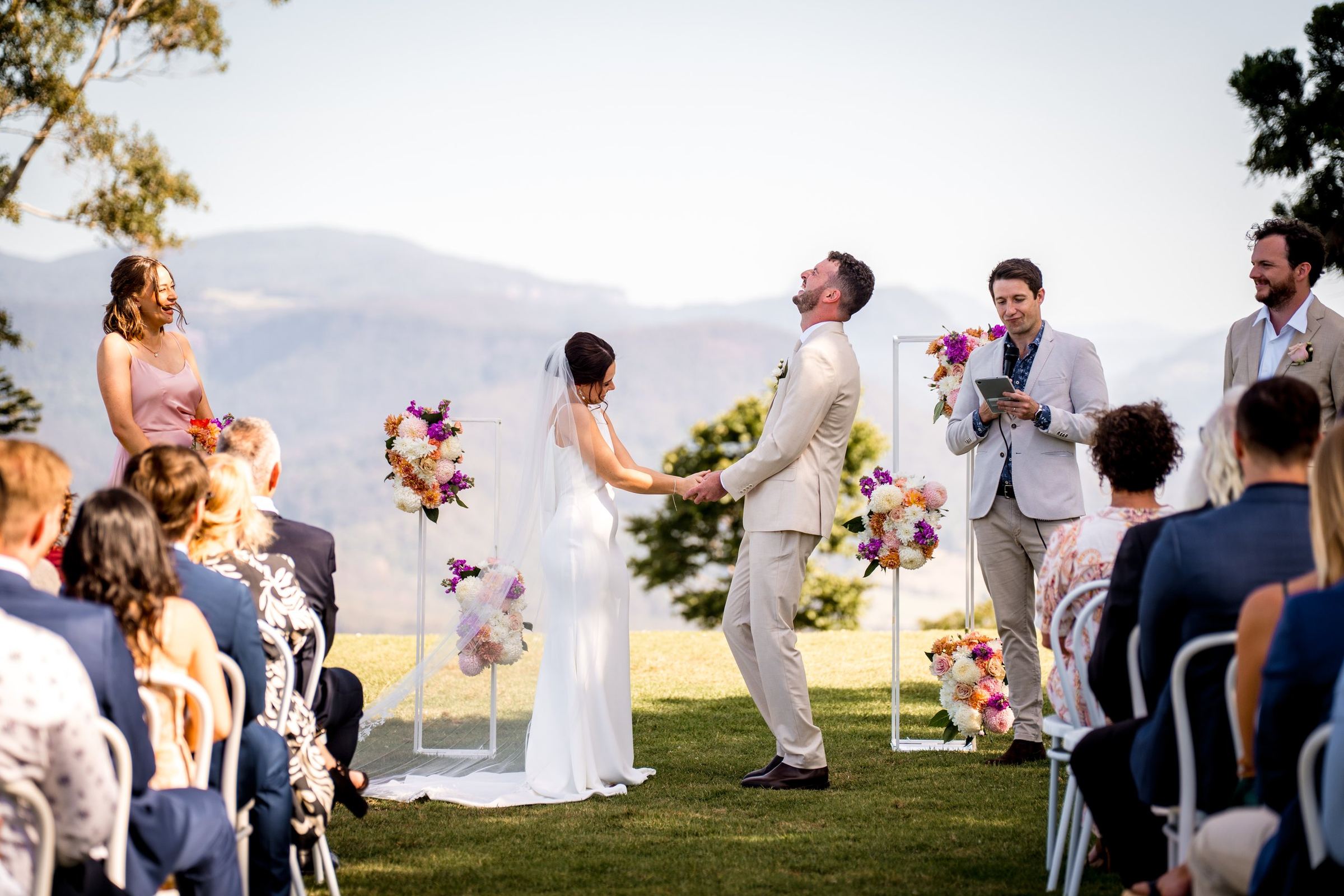 A couple exchanging vows on the lawn with the coast behind