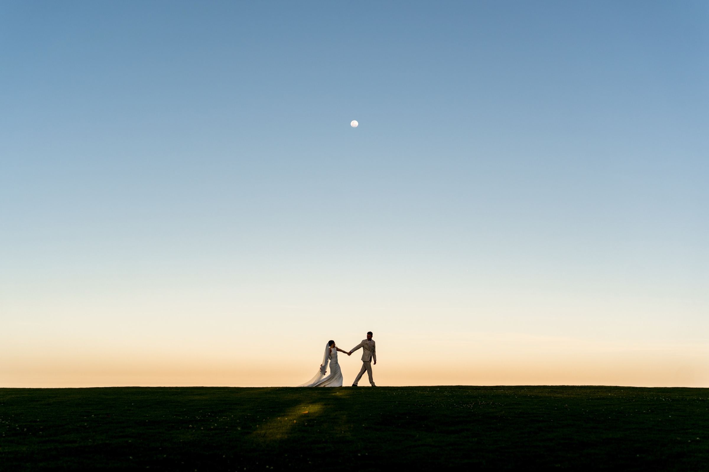 Couple at sunset with the moon in the background
