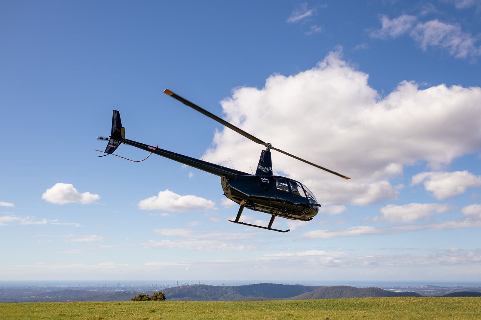 A helicopter banking over the valley and Hinze Dam