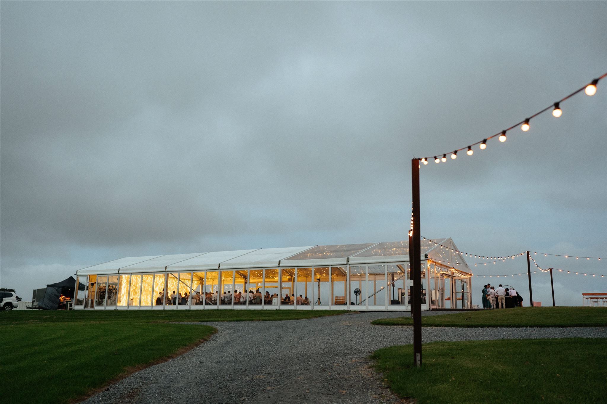 The marquee glowing at dusk across the lawn