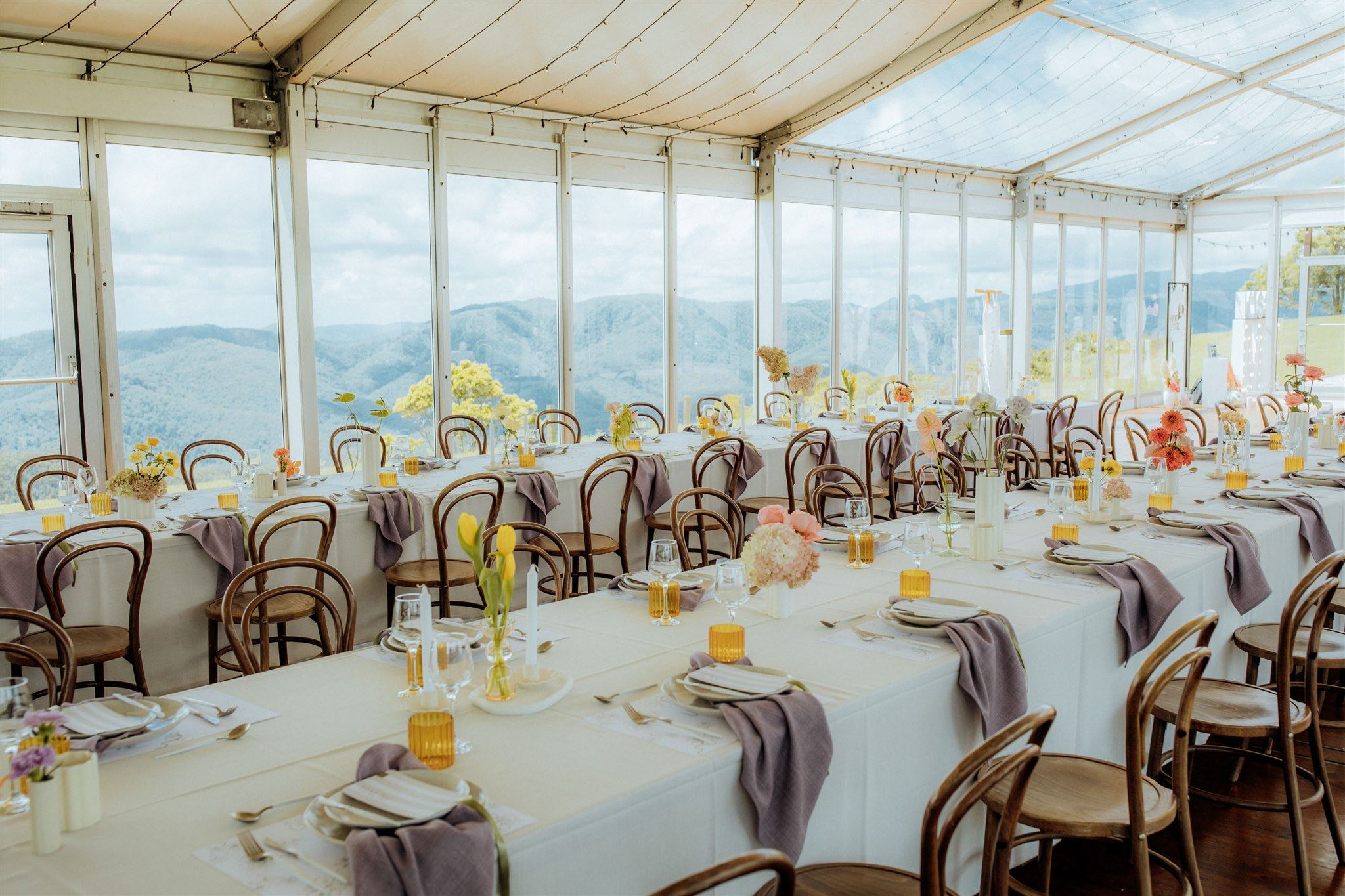 Long tables under the marquee's white summer roof, with the clear roof section beyond and the ranges through the glass walls